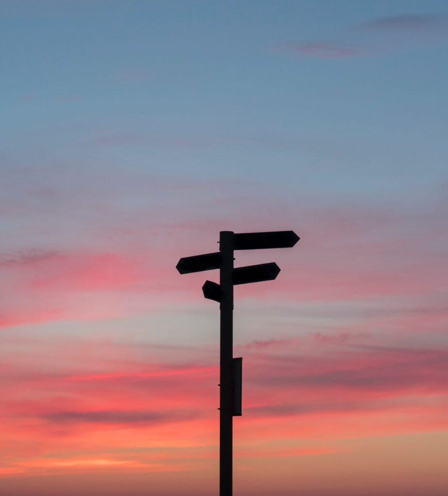 silhouette of direction signs against a sunset